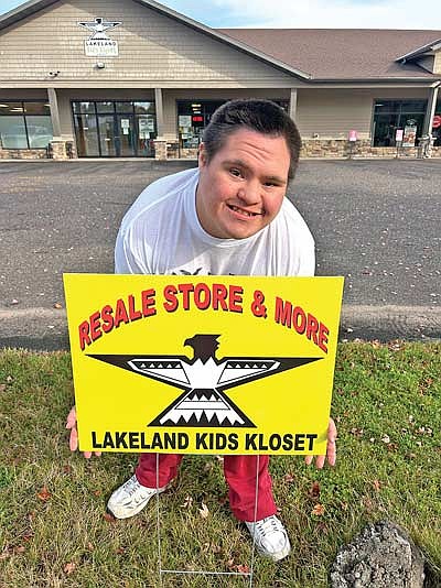 Student Cameron Jack stands in front of the new sign at Lakeland Kids Kloset, 9832 Plaza Drive in Minocqua. (Contributed photograph)