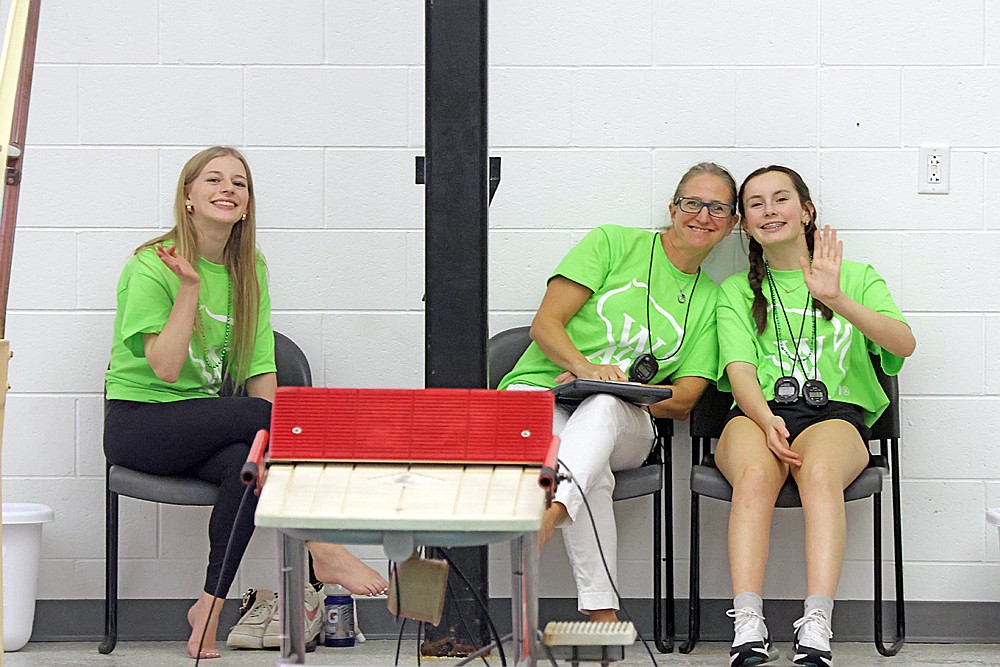 Volunteer timers Kyree McMahon, Terri Mickevicius and Lola Beach, all from Rhinelander, wave for a photograph during the WIAA Division 2 state girls’ swim meet in Waukesha Friday, Nov. 14. (Jeremy Mayo/River News)