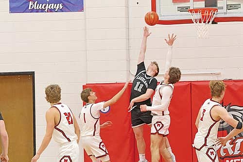 Jackson Burnett scores a basket with Medford’s Nick Krause (1) and Will Daniels defending in the second half of a conference game Friday, Dec. 12 at Raider Hall in Medford. Burnett led all scorers with 22 points. (Photo by Matt Frey/Star News)