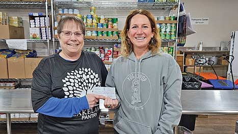 Lakeland Pantry director Lorna Springate accepts a $1,500 donation check from Breia Tlusty of the Yoga Shop. (Contributed photograph)