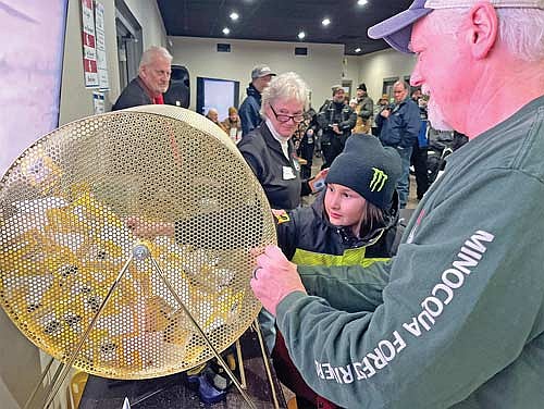 Isabella St. Louis, 8, pulls the winning raffle ticket for the fundraiser’s ultimate prize, a brand new snowmobile, a 2024 Ski Doo MXZ X-RS, with the help of club member John Ryan during the inaugural Vintage Snowmobile Day at Area 31 on Saturday, Feb. 22, 2025 in Minocqua. Club members Steve Andersen and Sue Ramirez look on. (Photo by Trevor Greene/Lakeland Times)