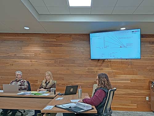 Getting a look at the guy wire plans in Bug Tussel’s proposal to place a tower on Rookery Run are, from left, Newbold town chairman Dan Hess, clerk Kim Gauthier and treasurer Jodie Hess at the Newbold town board meeting Feb. 12. (Photo by Ardith Carlton/River News)