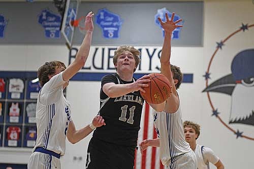Jackson Burnett scores a basket in-between two Merrill defenders in the second half of a conference game Thursday, Feb. 26 at Merrill High School. Burnett scored a varsity career-high 31 points. (Photo by Brett LaBore/Lakeland Times)