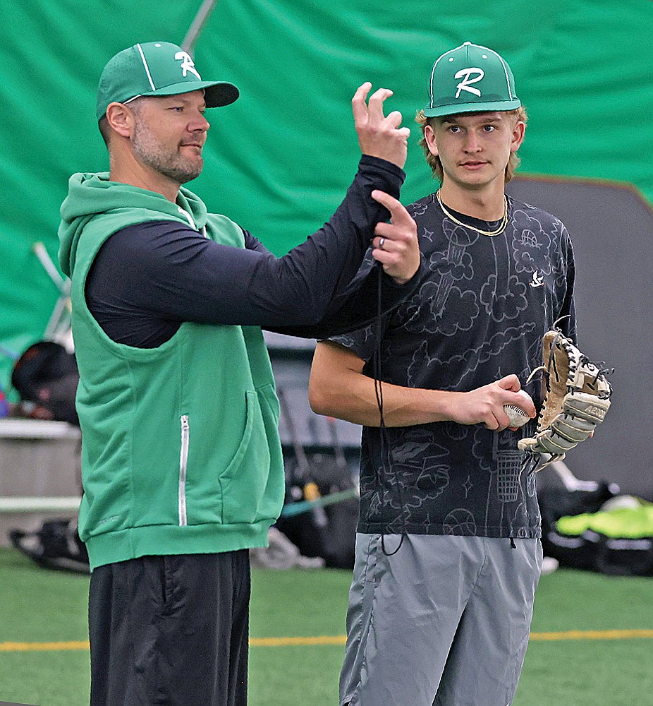 Rhinelander High School baseball coach Joe Waksmonski, left, demonstrates a pitching grip to junior Abe Gretzinger during practice in the Hodag Dome Monday, March 23. The Hodags started practice for the season on Monday. (Bob Mainhardt for the River News)