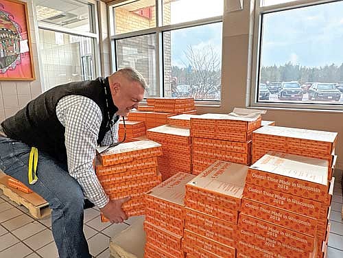 MHLT district administrator and principal Bob Smudde picks up a pile of kringles while helping load parents up on Friday, March 27, in Minocqua. (Photo by Trevor Greene/Lakeland Times)