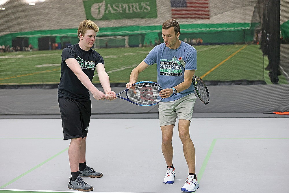 Rhinelander High School boys’ tennis coach Matt Nichols, right, works with freshman Kellen O’Malley on his stroke during practice in the Hodag Dome Monday, March 30. Monday was the first day high school boys’ tennis teams could practice in Wisconsin. (Bob Mainhardt for the River News)