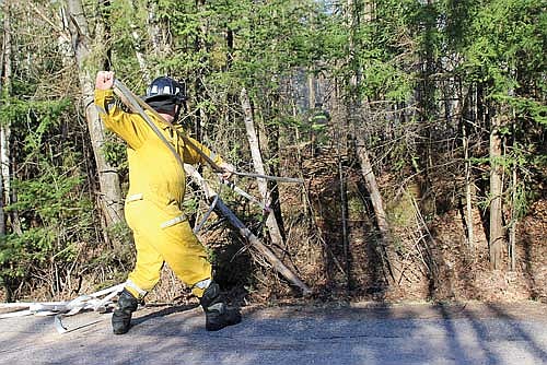Dealing with difficult terrain, firefighters carry hoses into the woods to battle a slow-moving but determined brushfire in Pelican on April 16. (Photo by Ardith Carlton/River News)