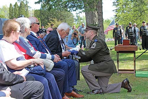 John Ginzl’s oldest living relative Richard Ginzl receives the flag from U.S. Army Master Sgt. Alexander Dennis at Forest Home Cemetery last Sunday. John Ginzl’s cremains are in the box on the table at right.
(Photo by Ardith Carlton/River News)