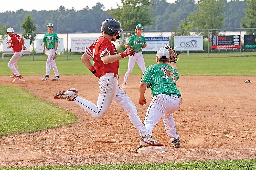 Antigo’s Levi Binversie beats out a throw to first fielded by Rhinelander’s Douglas Hartmann during the eighth inning of a Wisconsin Class AA Legion regional tournament game at Stafford Field Saturday, July 25. The throw came following a bobble by Rhinelander’s Henry Schmitz, one of eight errors the Rebels committed in a season-ending 9-6 loss to the Typhoon. (Bob Mainhardt for the River News)